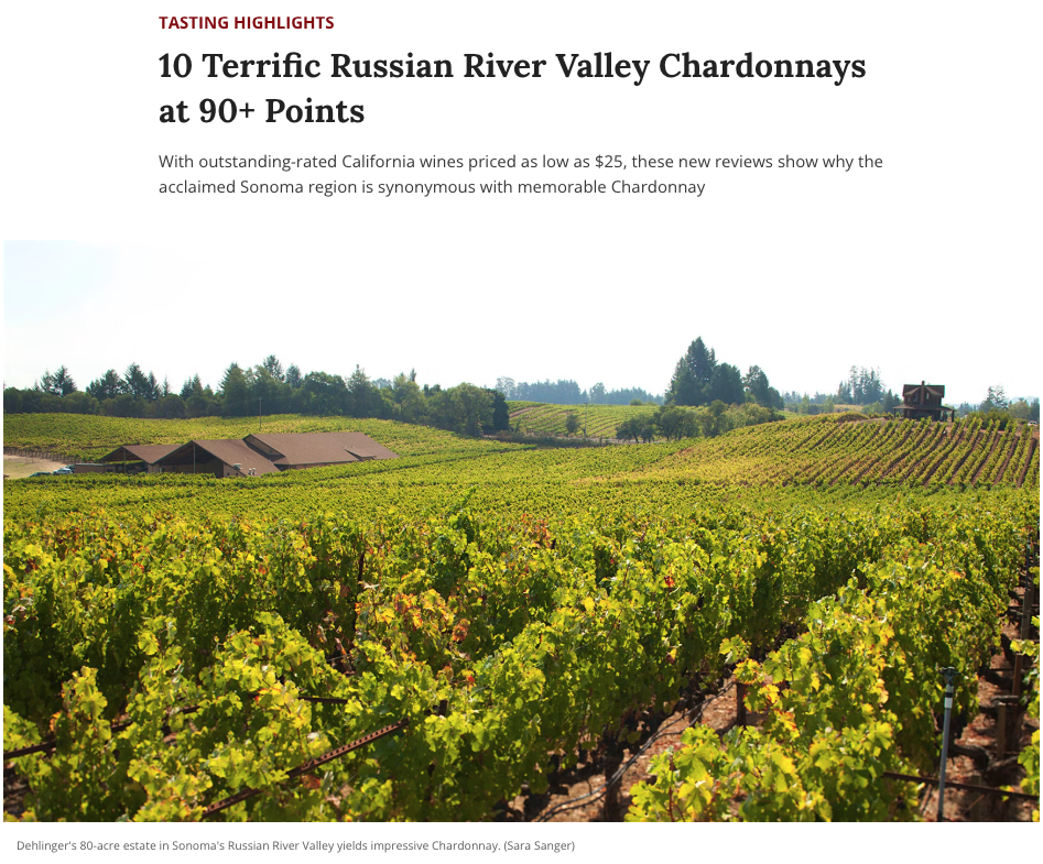 A scenic view of a vineyard in Sonoma's Russian River Valley, with lush green grapevines stretching across rolling hills. A brown-roofed building is nestled among the vines, and a wooden windmill structure is visible in the distance. The image accompanies an article highlighting top-rated Chardonnay wines from the region.